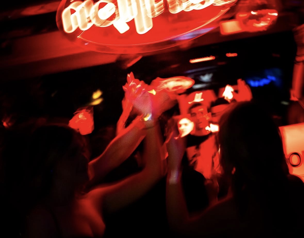 Hands in the air under the CARILLON neon sign